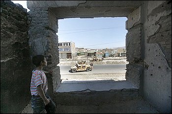 An Afghan boy looks out from a building, a day before the presidential election, in Kabul, Afghanistan, Wednesday, Aug. 19, 2009 as U.S. troops patrol in the area. (AP Photo/Rafiq Maqbool)